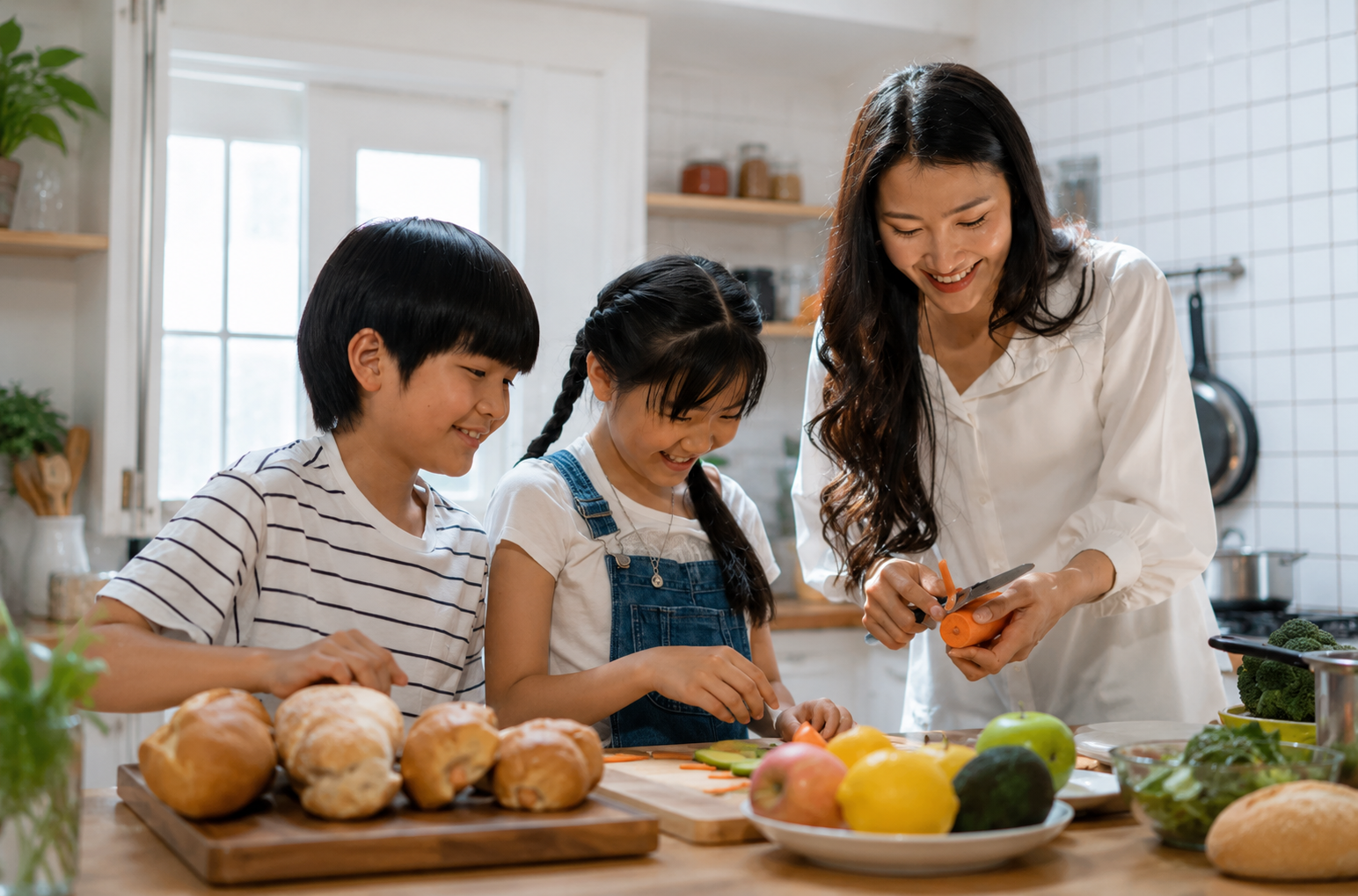 Famille en cuisine préparant des légumes et fruits frais autour d’un plan de travail, enfants souriants et adulte aidant, dans une cuisine lumineuse.